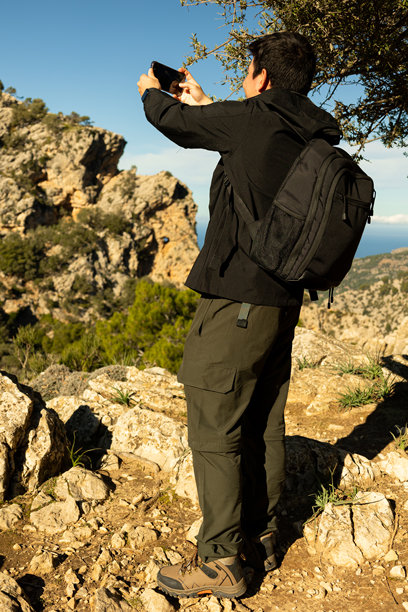 一名男子在山顶用手机拍照的竖版图片图片下载