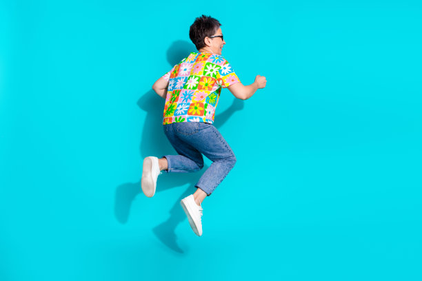 优雅的年长女性在青色背景上跳跃，展现出充满活力的全身侧面照片。图片下载