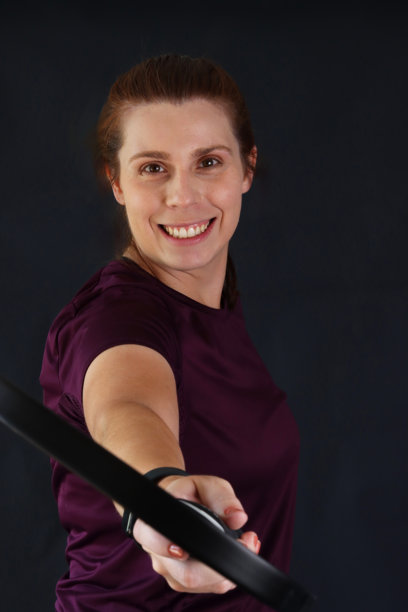 女人微笑着手持乒乓球拍并指向镜头。竖版照片，展现一位手持乒乓球拍的女性。图片下载