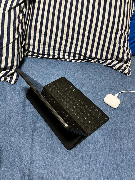 在舒适的床上，平板电脑、键盘和耳机的居家办公设置库存照片图片下载