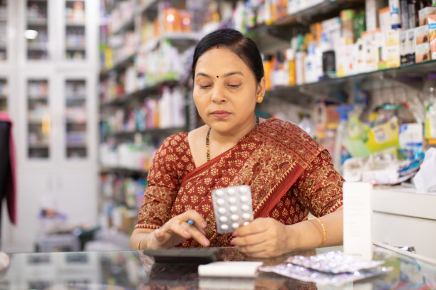 女性药剂师在药店检查库存药品 - 库存照片图片下载
