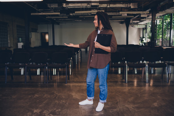 年轻女商人在室内商务中心的会议室展示邀请函的全身照片，手持夹板。图片下载