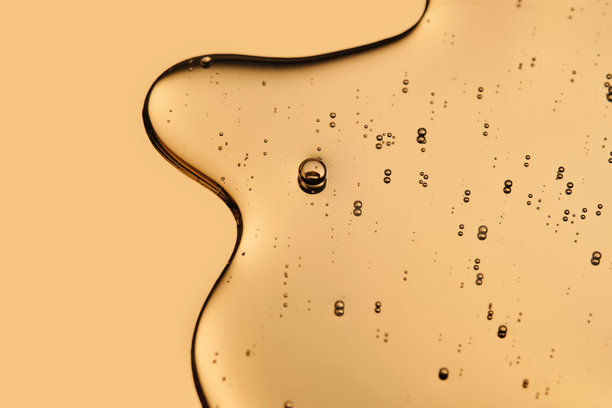 在金色背景上，化妆品精华的美丽质感占据了照片的大部分。图片下载