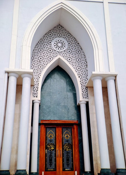 宏伟的清真寺入口，装饰着精美的木门，门上有复杂的书法和彩色玻璃。这张照片捕捉了伊斯兰建筑的美丽和灵性。图片下载