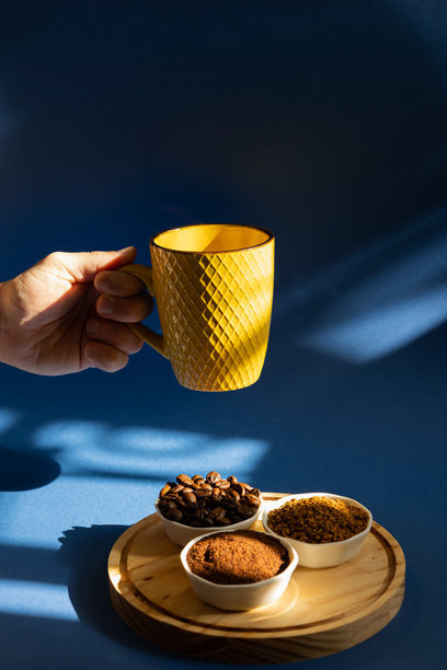 男性手握着一只黄色咖啡杯，旁边放着几只装有不同咖啡种类的小碗的竖版图片图片下载