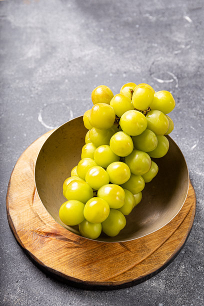 一束生机勃勃的新鲜麝香绿葡萄放在质朴的木板上，健康的小吃，竖版照片图片下载