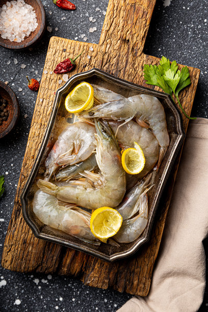 深灰色背景上的盘子和木板上的生虾，俯视垂直照片图片下载