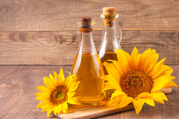向日葵油的特写照片，背景为木质桌面，旁边有种子。生物和有机产品概念。图片下载