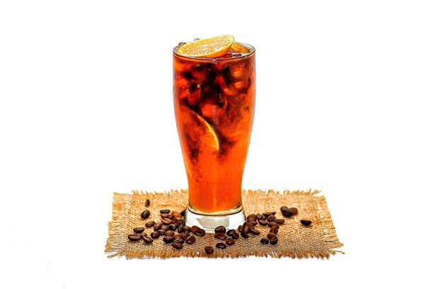 美式冰咖啡混合橙汁的图片，橙汁片放在麻袋上，咖啡豆散落在白色背景上，突出孤立的概念。图片下载
