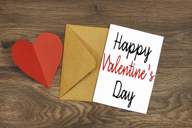 情人节快乐的概念。俯视照片展示白色请柬与手工信封和红色心形纸片放在木桌上。图片下载