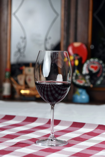 背光剪影下的玻璃桌上放着一杯红酒，浪漫的照片图片下载