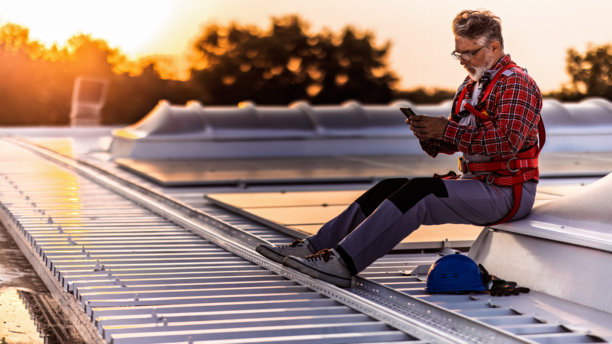 技术人员检查安装在建筑屋顶的太阳能发电厂的库存照片图片下载