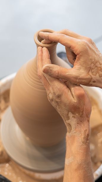 陶艺师的双手在陶轮上制作陶瓷花瓶的特写。竖版照片。图片下载