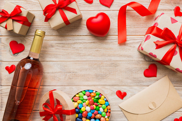 情人节装饰购物的俯视图照片，包，酒，瓶子，信封，礼物，盒子，糖果和红色的心在彩色背景与空白的空间。帧的背景图片下载