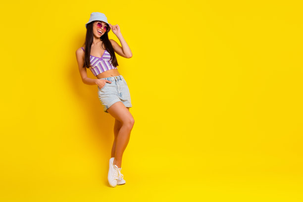 可爱的纤细女性在海洋上日光浴的全身照片，背景为黄色。图片下载