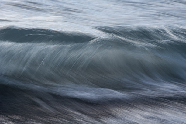 长时间曝光的海浪照片，展现出模糊的运动。水面反射着日落时分天空的色彩。图片下载