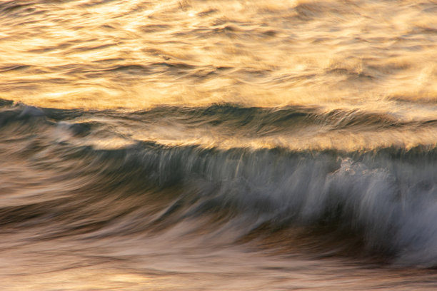 长时间曝光的海浪照片，展现出模糊的运动。水面反射着日落时分天空的色彩。图片下载