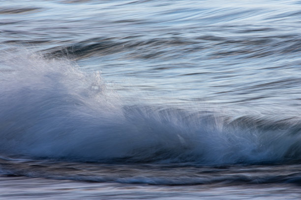 长时间曝光的海浪照片，展现出模糊的运动。水面反射出日落时分天空的色彩。图片下载