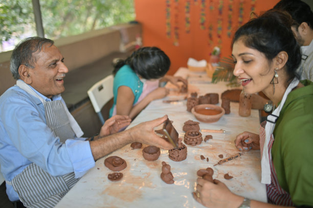 一位老年男子在陶艺工作坊上向一位女性参与者展示他在手机上拍摄的照片图片下载