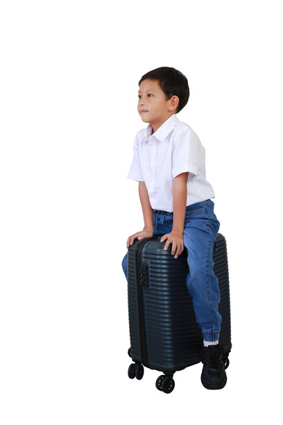 亚洲男孩骑在行李箱上，背景为白色。儿童与旅行的概念。全身照片。图片下载