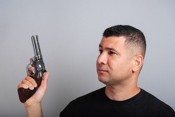 身穿黑色衬衫和牛仔裤的帅气男子手持枪械。图片下载