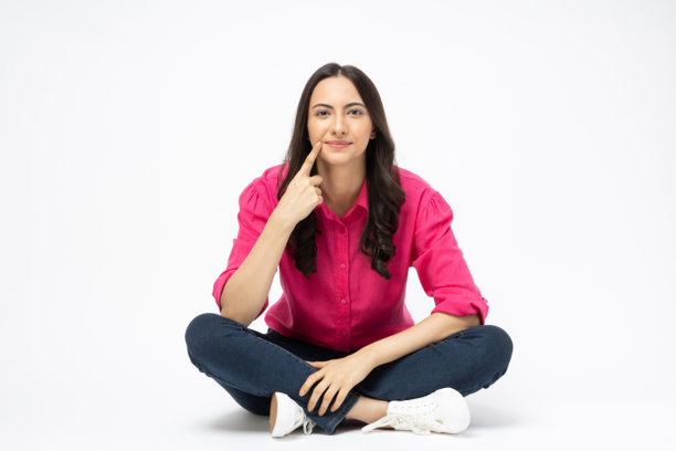 开朗可爱的女人穿着时髦的衣服，坐在地板空空间孤立的白色背景股票照片图片下载