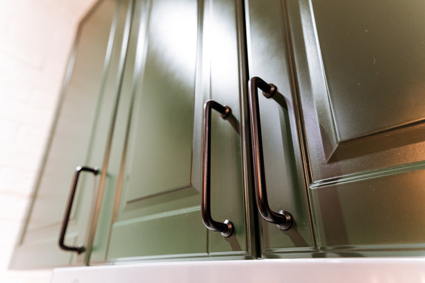 这张图片展示了生动的绿色橱柜的细致特写，优雅地搭配了光滑的黑色把手，突显了它们的现代设计和功能性。图片下载