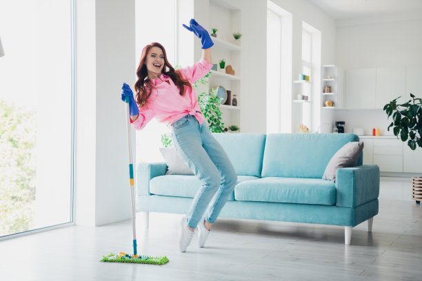 年轻漂亮的女人在现代明亮的公寓室内踮起脚尖跳舞，手里拿着拖把的全身照片图片下载