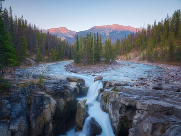 日出时的高山。岩石和森林中的瀑布。加拿大落基山脉。自然风光。适合明信片、壁纸和背景的图片。图片下载