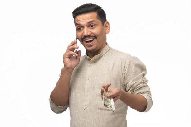 年轻印度男子在白色背景下打电话，手持印度货币的肖像照片图片下载