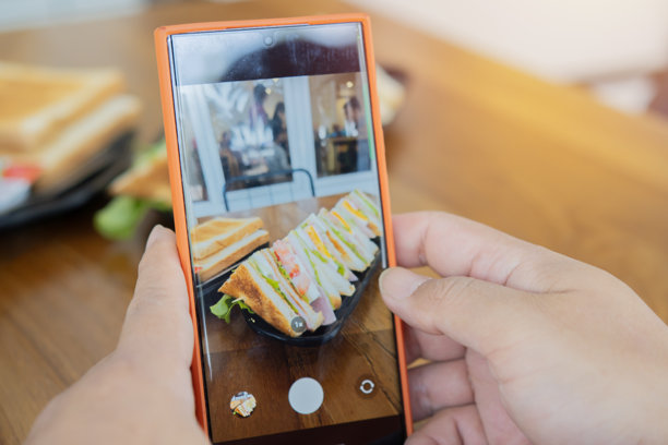 男性手用智能手机拍摄桌上三明治的早餐照片。图片下载