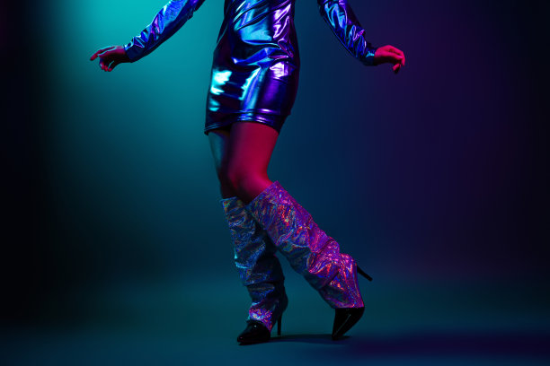 一张迷人的年轻女性穿着时尚的复古派对服装在黑暗背景下跳迪斯科的裁剪照片图片下载