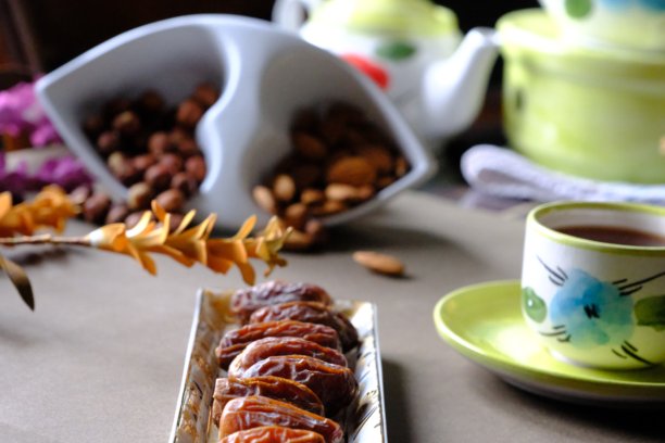 拉马丹开斋餐桌的特写照片，摆放着枣子、橄榄、茶壶和花卉装饰。图片下载