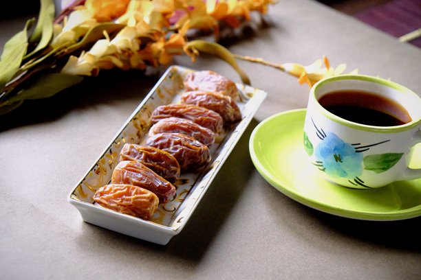 拉马丹开斋餐桌的特写照片，桌上有枣子、橄榄、茶壶和花卉装饰。图片下载