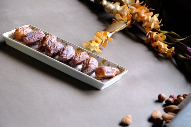 拉马丹开斋餐桌的特写照片，摆放着枣子、橄榄、茶壶和花卉装饰。图片下载