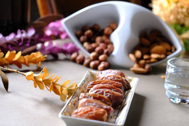 拉马丹开斋餐桌的特写照片，桌上有枣子、橄榄、茶壶和花卉装饰。图片下载