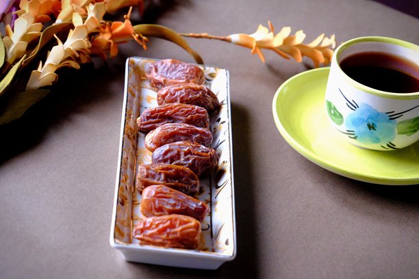 拉马丹开斋餐桌的特写照片，桌上有枣子、橄榄、茶壶和花卉装饰。图片下载