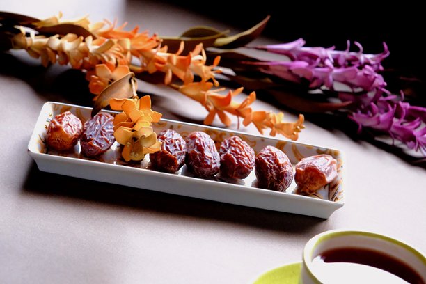 拉马丹开斋餐桌的特写照片，摆放着枣子、橄榄、茶壶和花卉装饰。图片下载