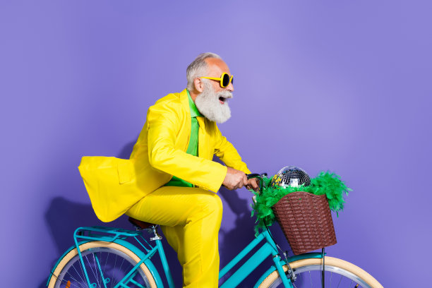 穿着时尚的幽默男士骑着自行车，侧面照片，目光投向空旷的空间，背景为紫色。图片下载