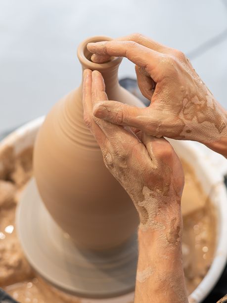 陶艺师的双手在陶轮上制作陶瓷花瓶的特写。竖版照片。图片下载