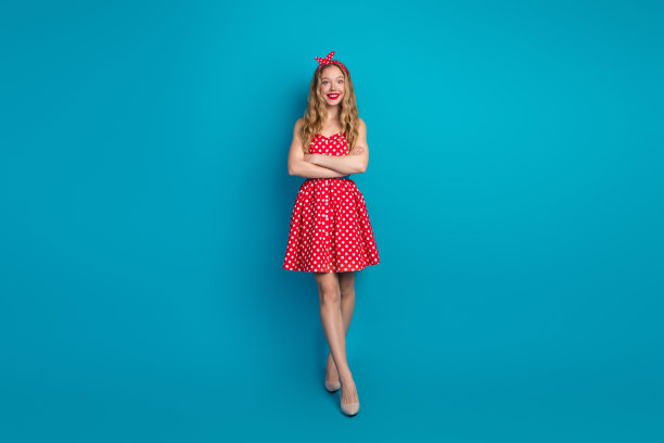 穿着红色波点裙的年轻女性在明亮的蓝色背景前摆姿势，展现复古的插画时尚风格。图片下载
