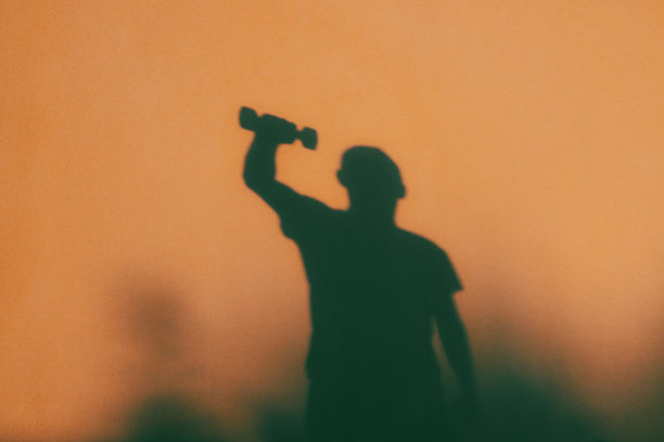 一名年轻男子手持哑铃的影子。运动。健康生活方式。男性身影的照片。图片下载