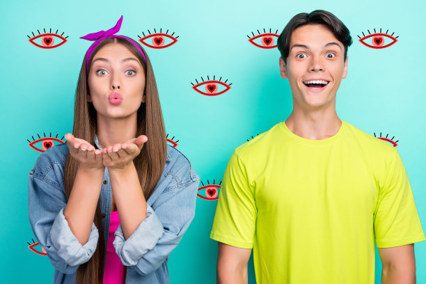 可爱的棕发千禧一代情侣穿着黄色和粉色T恤、牛仔裤，在青色背景前吹吻的照片图片下载