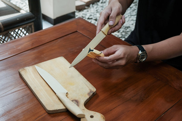 特写照片：男人在厨房桌子上用专用磨刀器磨刀。图片下载