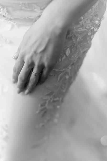 新娘的手轻轻放在大腿上，佩戴着闪亮的订婚戒指。这张黑白照片中，亮片礼服熠熠生辉。图片下载