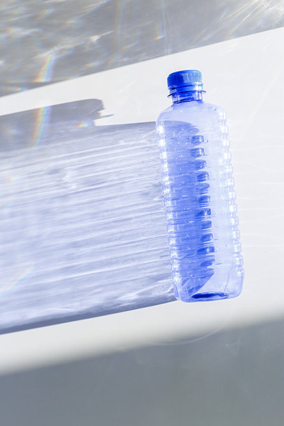 清晰的塑料水瓶，装满洁净的水，背景为白色和蓝色，特写，极简美学生活照片，俯视图，平铺，天然光，阳光阴影，光线折射效果，星形滤镜图片下载