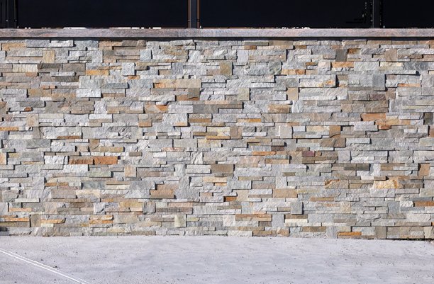 假石饰面墙和顶部黑色金属面板制成的围栏。混凝土地面。图片下载