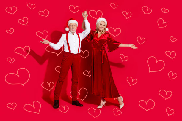 穿着复古优雅裙子和吊带的老年舞者在红色背景下的全身照片，庆祝圣诞派对。图片下载