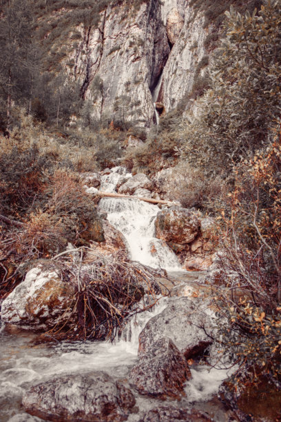 皮斯恰杜瀑布在岩石悬崖间倾泻而下，周围环绕着阿尔卑斯绿色植被和流动的小溪，呈现出复古风格的照片。图片下载