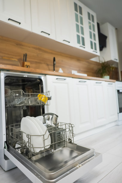 开放式洗碗机区域的竖版照片，干净的盘子和餐具在明亮的厨房背景下，白色橱柜和木质台面及面板。洗碗、清洁和减轻家务的概念。图片下载
